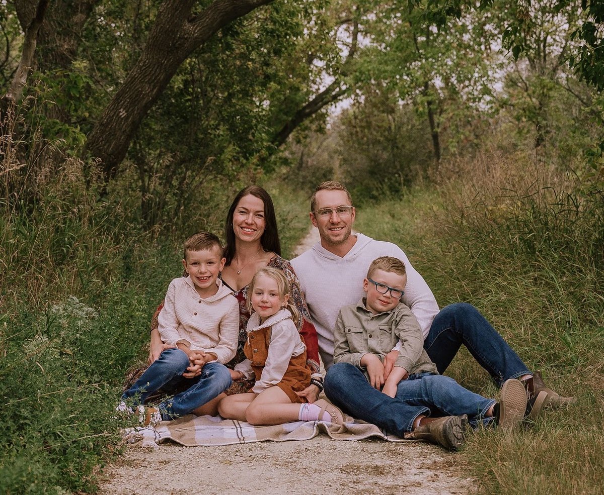 Trevor Perron with his wife and three children on a tree-lined path